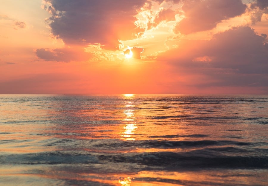 sunset over the ocean with clouds